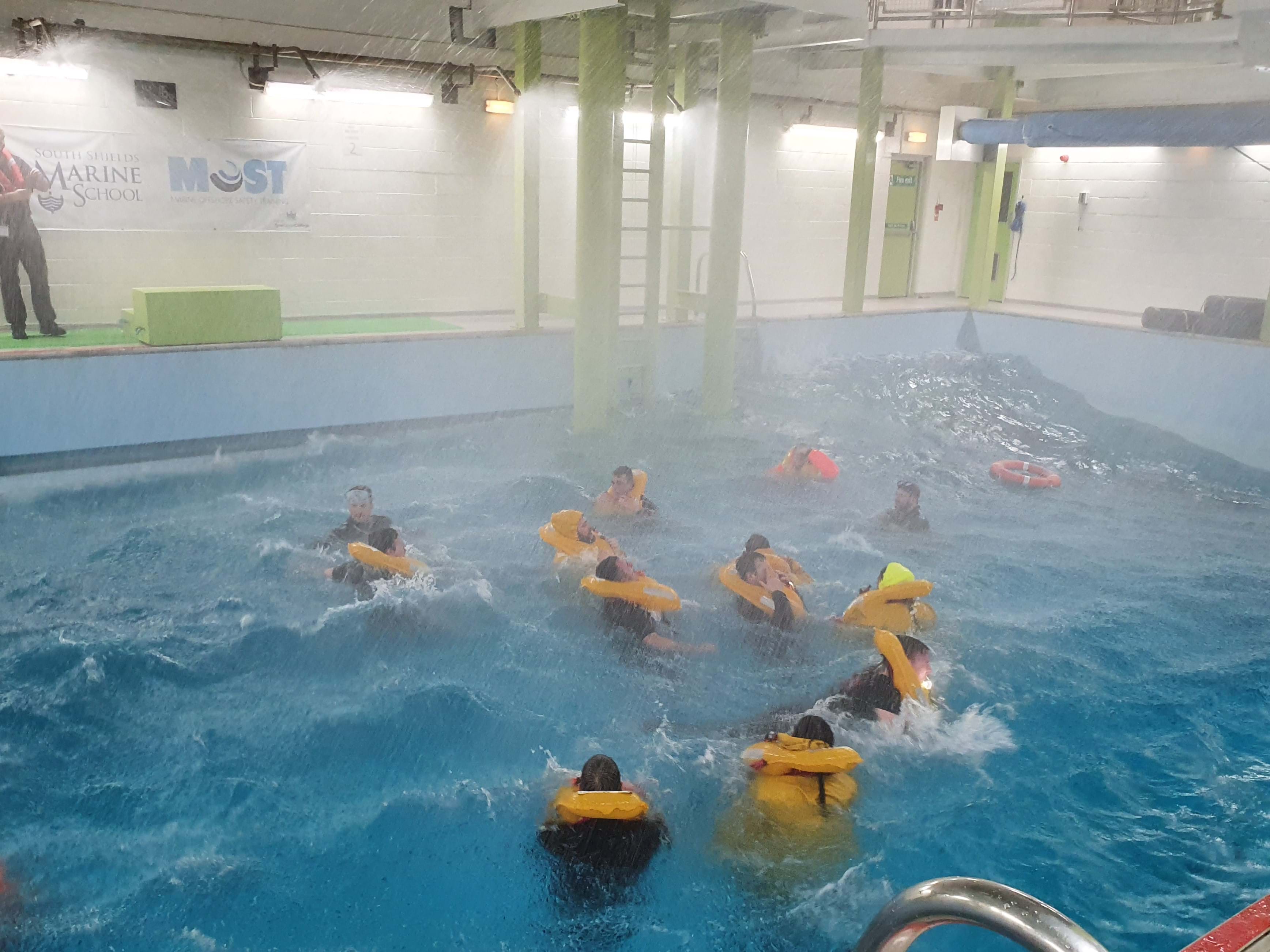 作为训练练习的一部分，一群戴着漂浮装置的人在训练游泳池里。